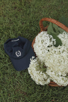 Navy cotton dad cap with cream embroidered Signature Homemaker's Club Crest on front and Homemaker's Club embroidered on back.