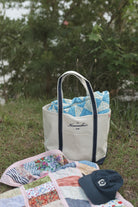 The Everyday Tote, a natural canvas boat tote with navy trim and The Everyday Cap, a navy embroidered cotton dad cap from The Homemaker’s Club